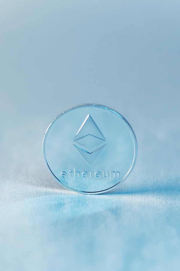 Ethereum cryptocurrency coin standing upright on a light blue background