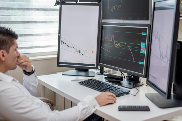 Trader reviewing cryptocurrency price charts on multiple monitors