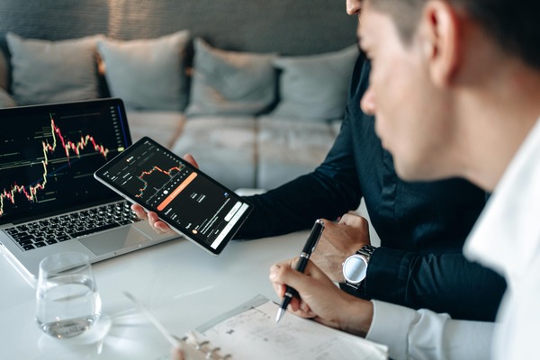 Traders reviewing cryptocurrency price charts on a tablet and laptop