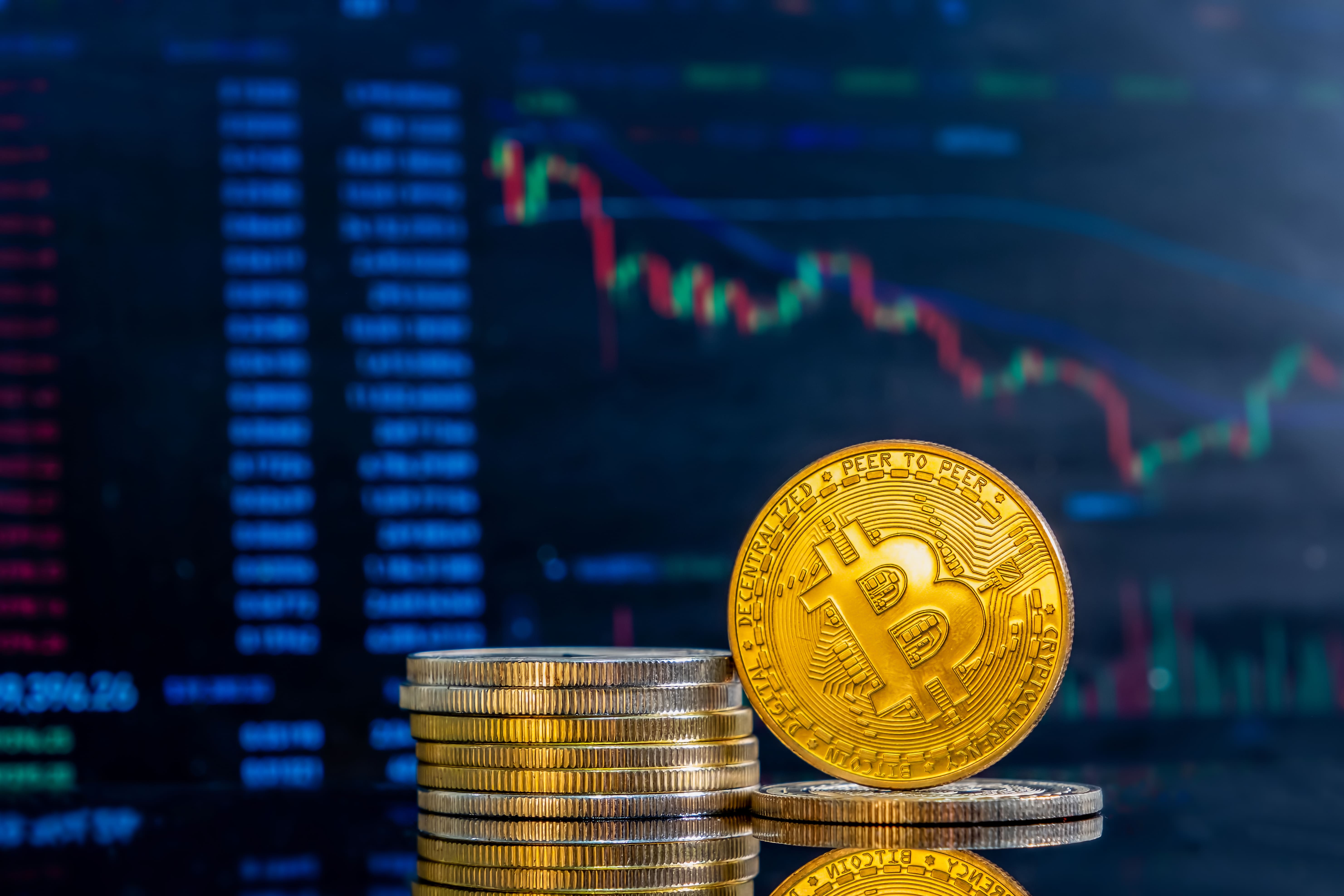 Bitcoin-style cryptocurrency coin with a stack of coins in front of a market price chart