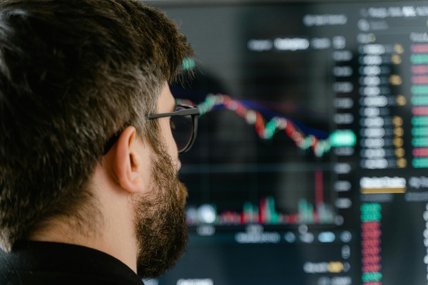 Person reviewing cryptocurrency trading data across multiple computer monitors