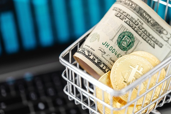 US dollar banknotes and Bitcoin-style cryptocurrency coins in a shopping basket