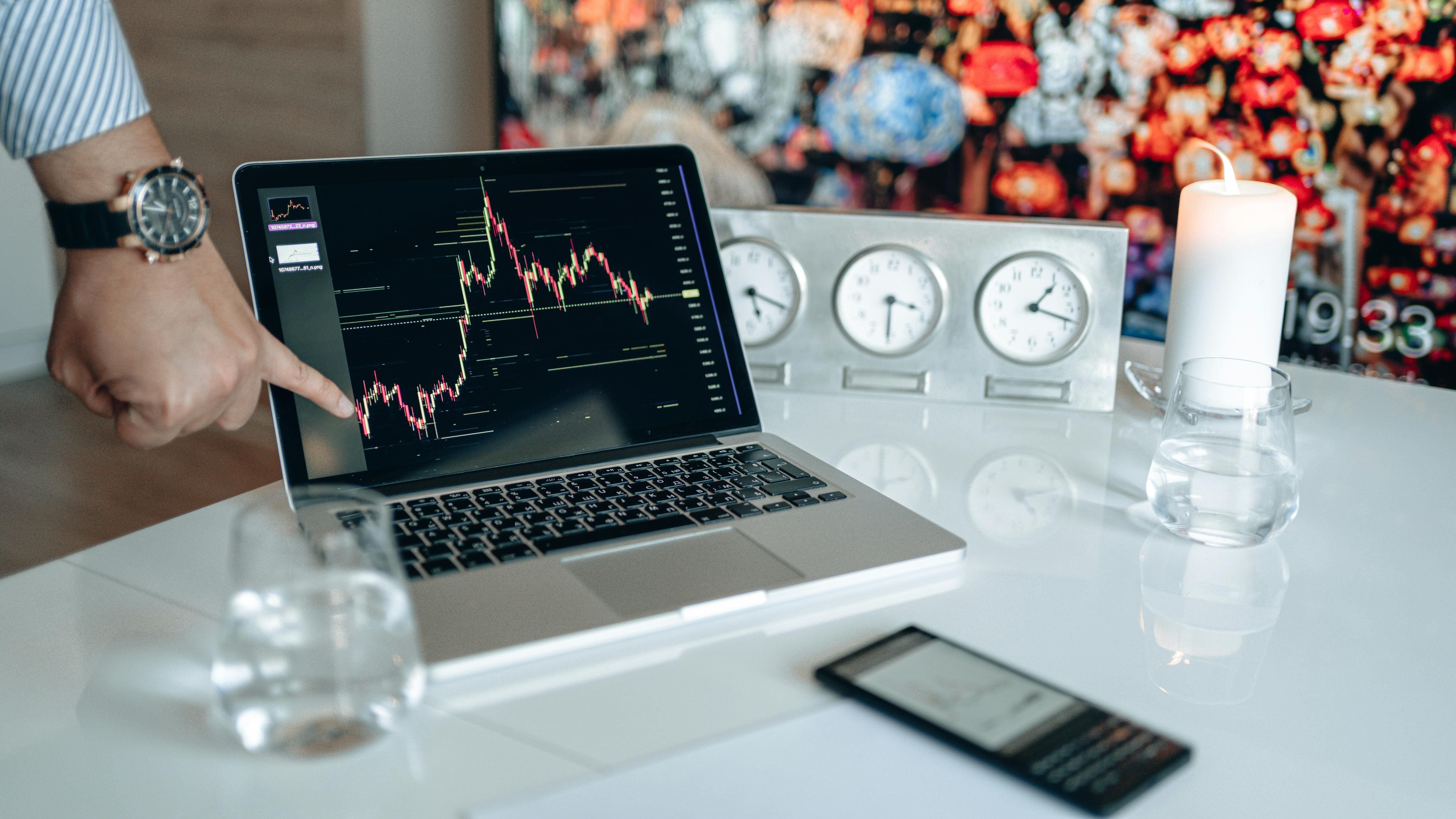 Laptop showing a cryptocurrency price chart next to a row of clocks representing network speed